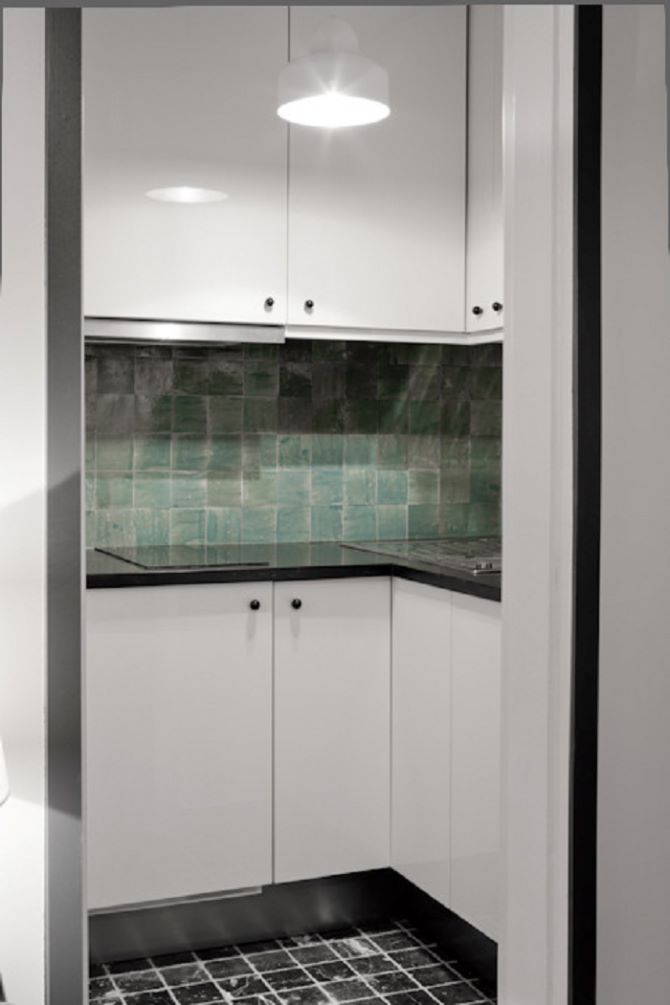Phòng bếp với gam màu đen - trắng hiện đại. Đi kèm đó là mảng tường xanh giúp không gian nấu nướng sống động hơn